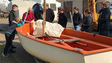 Kursteilnehmer lassen sich von einem Segellehrer die Funktionen eines Segelboots erklären